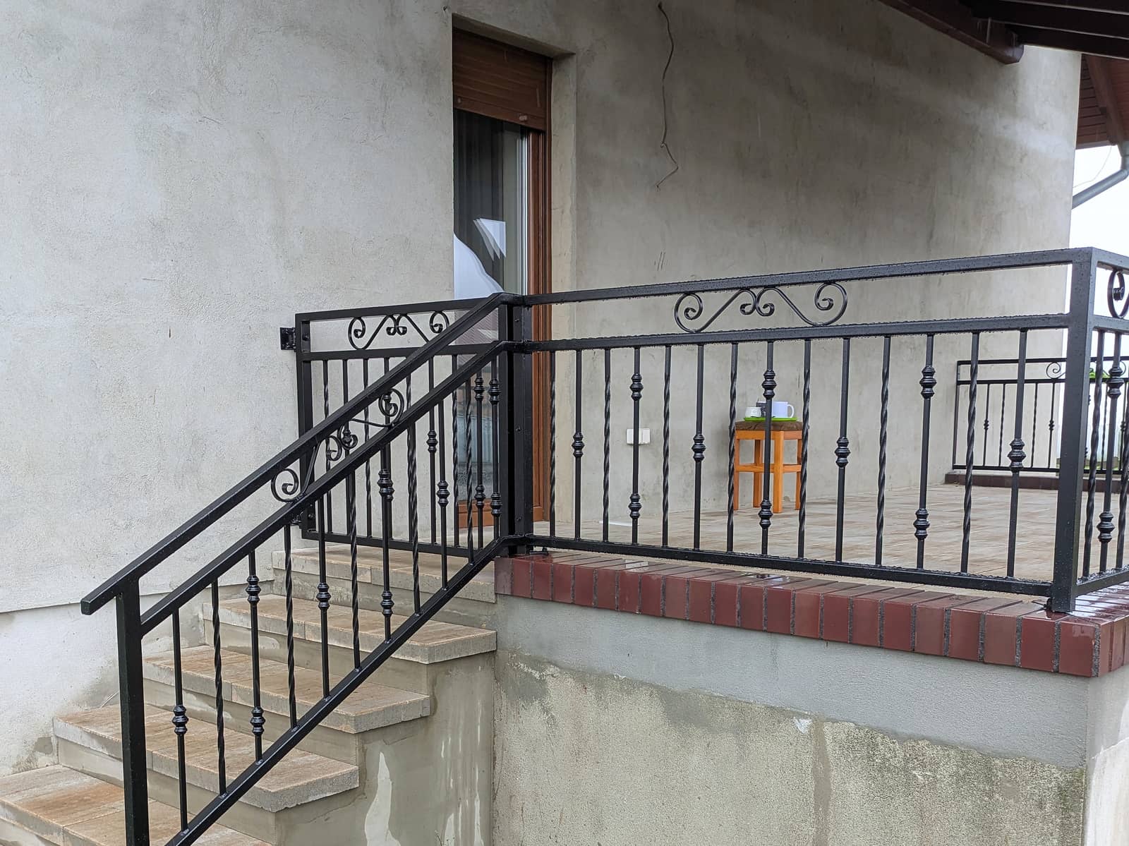 Kuta balustrada schodów i tarasu w jednym wzorze, z ozdobnymi ślimacznicami w górnej ramie