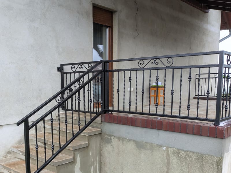 Kuta balustrada schodów i tarasu w jednym wzorze, z ozdobnymi ślimacznicami w górnej ramie