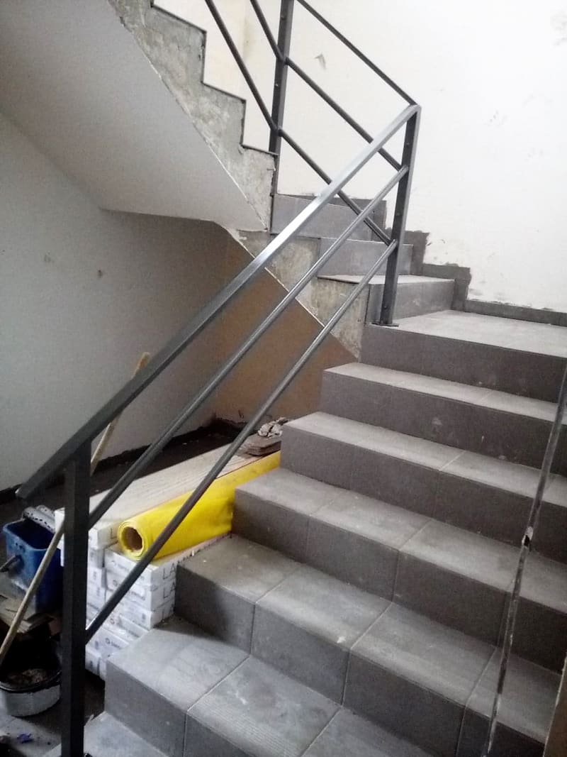 Montaż stalowej balustrady przy zewnętrznych schodach betonowych
