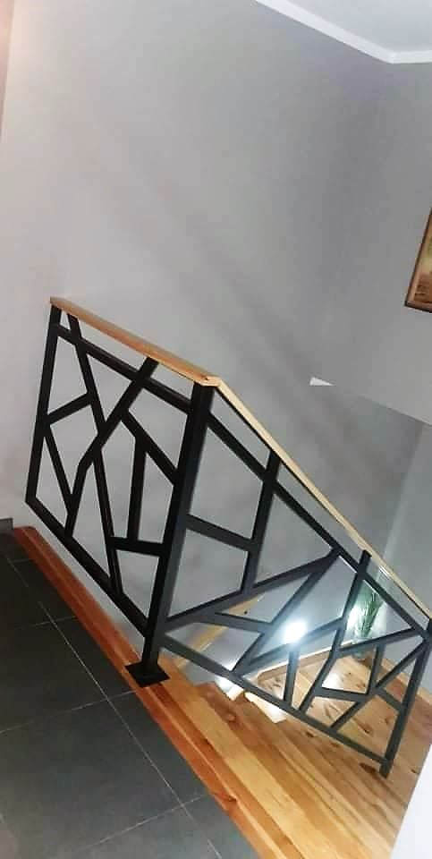 Balustrada schodowa o nieregularnym wzorze geometrycznym z drewnianym pochwytem