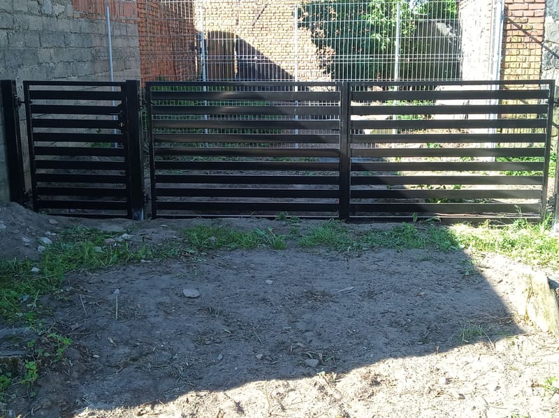 Brama przesuwna z czarnych lameli poziomych na wjeździe na posesję