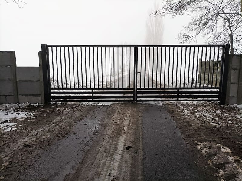Brama dwuskrzydłowa z pionowych prętów stalowych na wjeździe na posesję