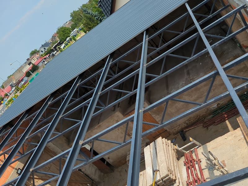 Stalowa konstrukcja dachu z kratownic z rozpoczętym montażem pokrycia z blachy trapezowej