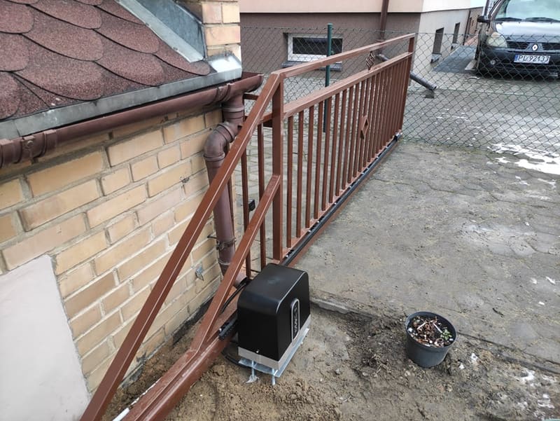 Napęd do bramy przesuwnej osadzony na fundamencie przy wjeździe na posesję