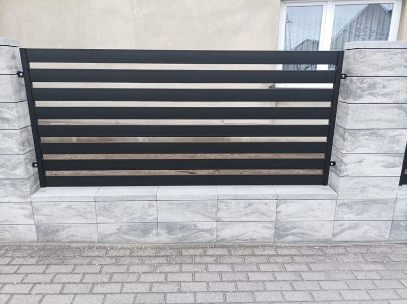 Przęsło o poziomym wypełnieniu antracytowym osadzone na murze z betonu architektonicznego
